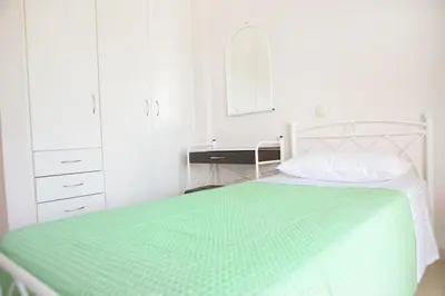 a white bedroom with a green bed and a sink at Butterfly Estates Maritsa Rhodes in Pastida