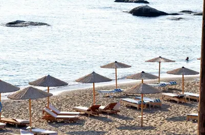 a group of chairs and umbrellas on a beach at Stegna Akti Luxury Suites in Archangelos