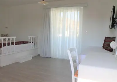 a white room with a dining table and a window at Stegna Akti Luxury Suites in Archangelos