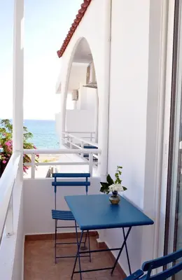 a blue table and chairs on a balcony with the ocean at Stegna Akti Luxury Suites in Archangelos