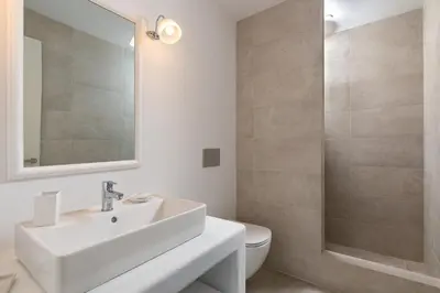 a white bathroom with a sink and a shower at Stegna Akti Luxury Suites in Archangelos
