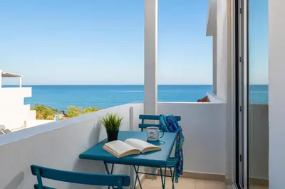 a blue table with books on a balcony with the ocean at Stegna Akti Luxury Suites in Archangelos