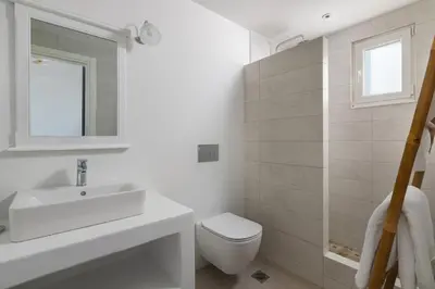a white bathroom with a sink and a toilet at Stegna Akti Luxury Suites in Archangelos