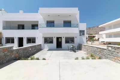 a large white house with a stone wall at Aegean Treasure Pefkos in Pefki Rhodes