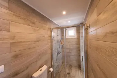 a bathroom with a toilet and wooden walls at Lindian Jewel Hotel and Villas in Líndos