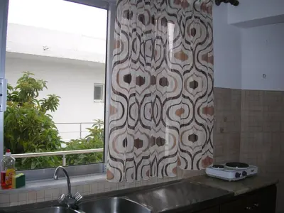 a kitchen with a shower curtain with a sink and a window at Maria Studios and Apartments in Haraki