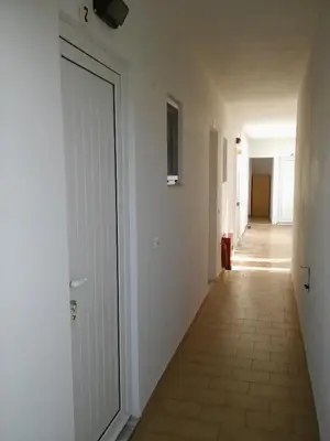 a hallway with a white door and a tile floor at Maria Studios and Apartments in Haraki