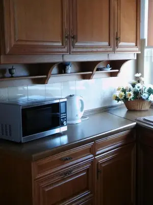 a kitchen with wooden cabinets and a microwave on a counter at Maria Studios and Apartments in Haraki