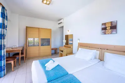 a bedroom with a bed and a table and a desk at Raffaello Beach in Faliraki
