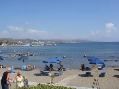 a group of people on a beach with blue umbrellas at Elpida Beach Studios in Faliraki