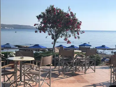 a group of tables and chairs next to the water at Elpida Beach Studios in Faliraki