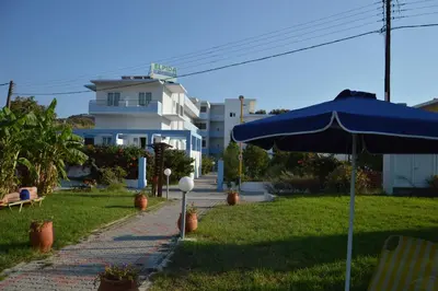 a blue umbrella sitting on a lawn in front of a building at Elpida Beach Studios in Faliraki