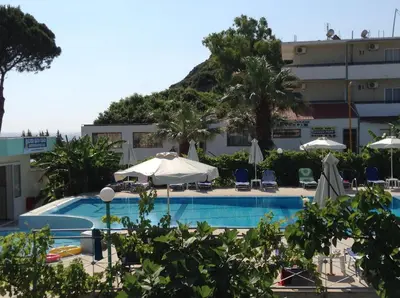 a pool with chairs and umbrellas in front of a building at Elpida Beach Studios in Faliraki