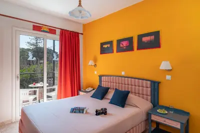 a bedroom with a bed with yellow walls and a balcony at Arte Annapolis Inn in Rhodes Town