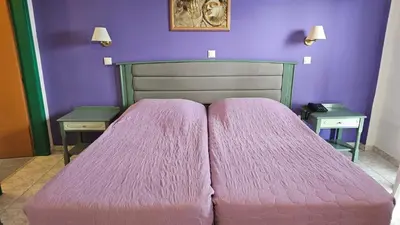 a bedroom with a pink bed with two tables at Arte Annapolis Inn in Rhodes Town