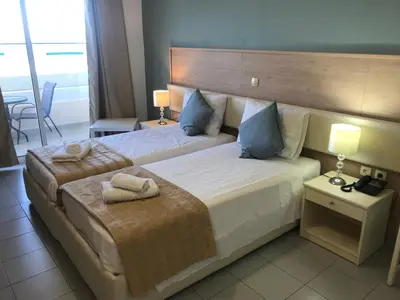 a bedroom with a large bed with towels on it at Bayside Hotel Katsaras in Kremasti