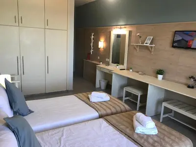 a room with two beds and a desk in it at Bayside Hotel Katsaras in Kremasti