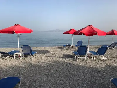 a group of chairs and umbrellas on a beach at Bayside Hotel Katsaras in Kremasti