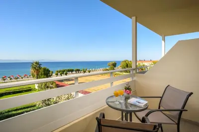a balcony with a table and chairs and a view of the beach at Bayside Hotel Katsaras in Kremasti
