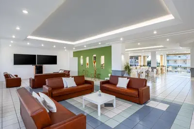a living room with couches and a tv at Bayside Hotel Katsaras in Kremasti
