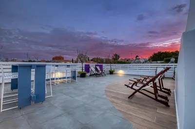 a rooftop deck with a table and chairs at sunset at Alley 7, Old Town in Rhodes Town