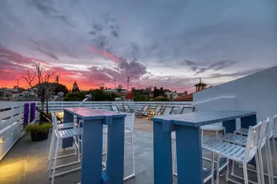 a blue table and chairs on a roof with a sunset at Alley 7, Old Town in Rhodes Town