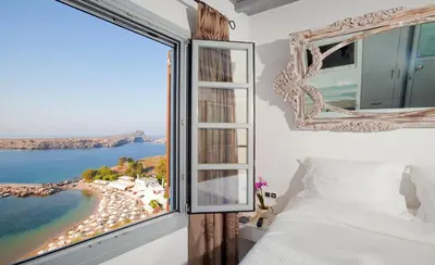 a bedroom with a window with a view of a beach at Lindos Shore Boutique Villa with sea view in Líndos