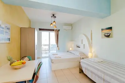 a room with two beds and a table with a table sidx sidx sidx at Christos studios and family apartments in Rhodes Town