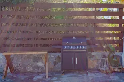 a grill and a picnic table under a wooden fence at Christos studios and family apartments in Rhodes Town