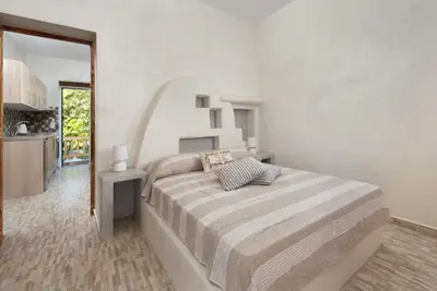 a bedroom with a large bed in a white room at Christos studios and family apartments in Rhodes Town