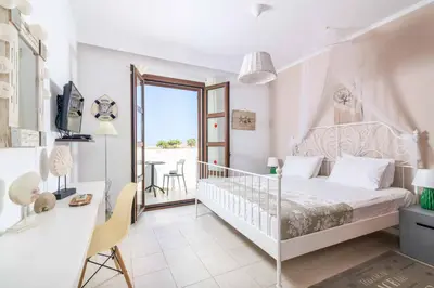 a white bedroom with a bed and a table and a desk at Lindos Ruby in Líndos