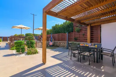 a patio with a table and chairs under a wooden pergola at Lindos Sapphire in Líndos