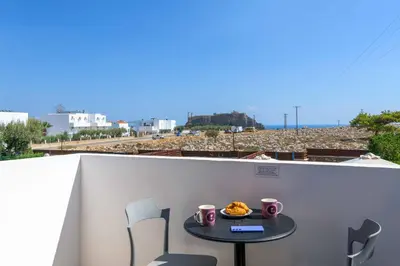 a small table with a plate of food on a balcony at Lindos Sapphire in Líndos