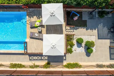 an overhead view of a swimming pool with white umbrellas and a swimming pool at Lindos Sapphire in Líndos