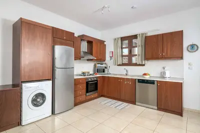 a kitchen with wooden cabinets and a washer and dryer at Lindos Sapphire in Líndos