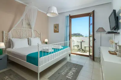 a bedroom with a bed and a balcony with a table at Lindos Topaz in Líndos