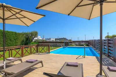 a swimming pool with two chairs and an umbrella at Lindos Topaz in Líndos