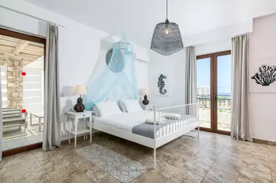 a white bedroom with a bed and a balcony at Villa Krini Selini in vlicha