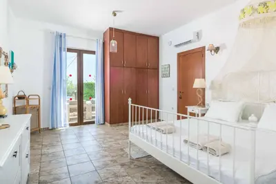 a bedroom with a white bed with a wooden cabinet at Villa Krini Selini in vlicha