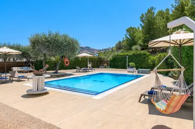 a pool with a hammock and chairs and an umbrella at Villa Krini Selini in vlicha