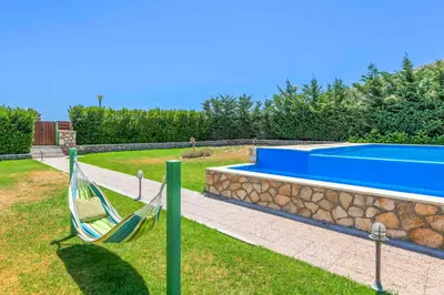 a hammock in a yard next to a swimming pool at Lindos Emerald in Líndos