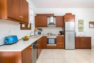 a kitchen with wooden cabinets and a stainless steel refrigerator at Lindos Emerald in Líndos