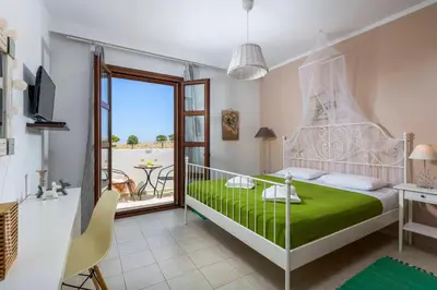 a bedroom with a green bed and a balcony at Lindos Emerald in Líndos