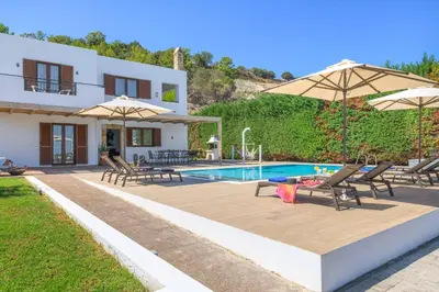 a villa with a swimming pool with chairs and umbrellas at Villa Krini Eleni in vlicha