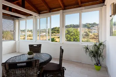 a dining room with a table and chairs and windows at Nicole's garden villa in Kallithea Rhodes