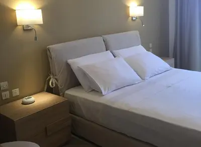 a bedroom with a bed with white sheets and pillows at Nikos Ikies in Theologos