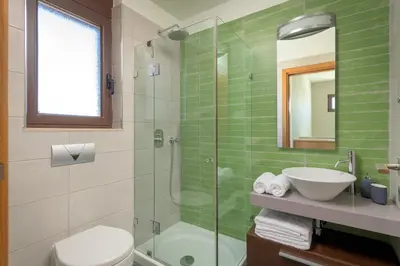 a bathroom with a glass shower and a sink at Alav Pool Villa in Afantou
