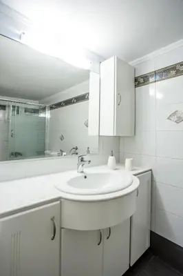 a white bathroom with a sink and a tub at Flora's Place in Rhodes Town
