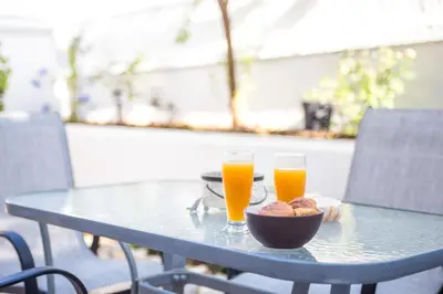 a table with two glasses of orange juice and a bowl of food at Flora's Place in Rhodes Town