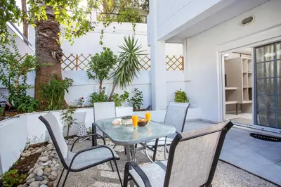 a patio with a table and chairs and a tree at Flora's Place in Rhodes Town